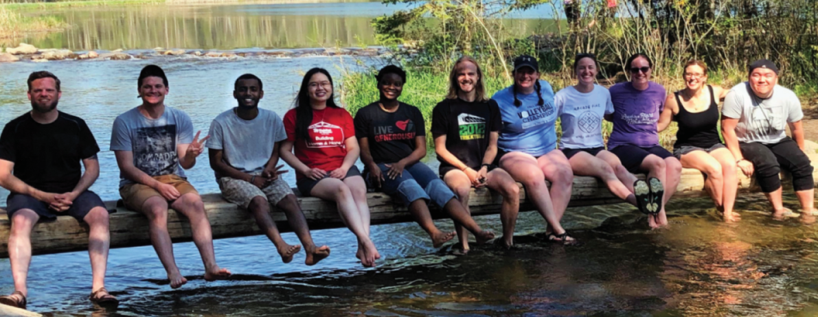 10 people sitting on log in nature